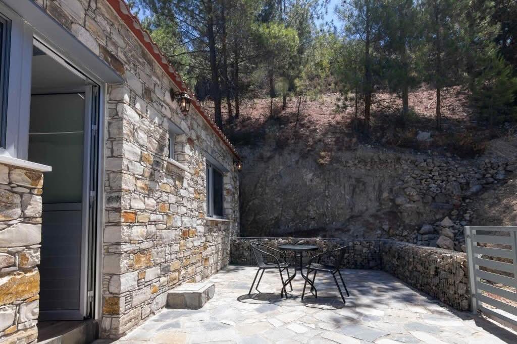 Shaded side terrace with a bistro table beside the stone facade and the rock cutting behind